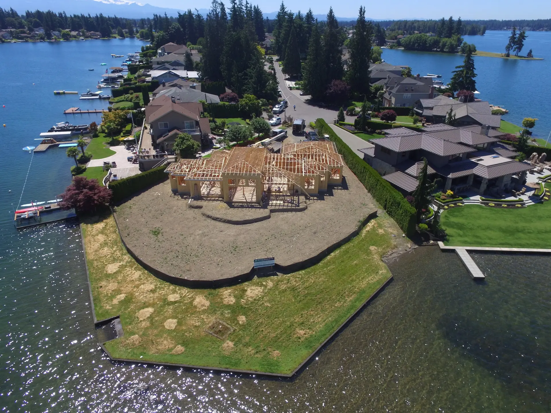 Aerial view of the same lot at framing, roof trusses set, water wrapping two sides