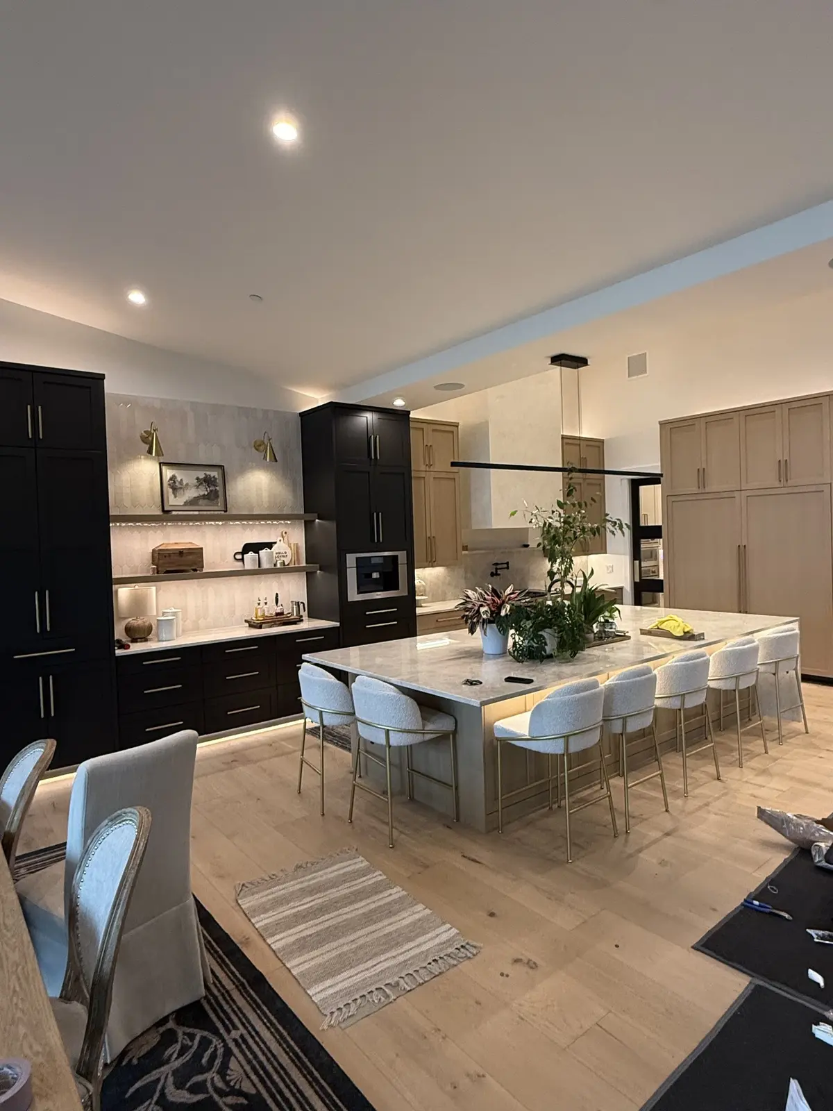 Kitchen in dark cabinetry with a long island, integrated appliances and pendants over the seating