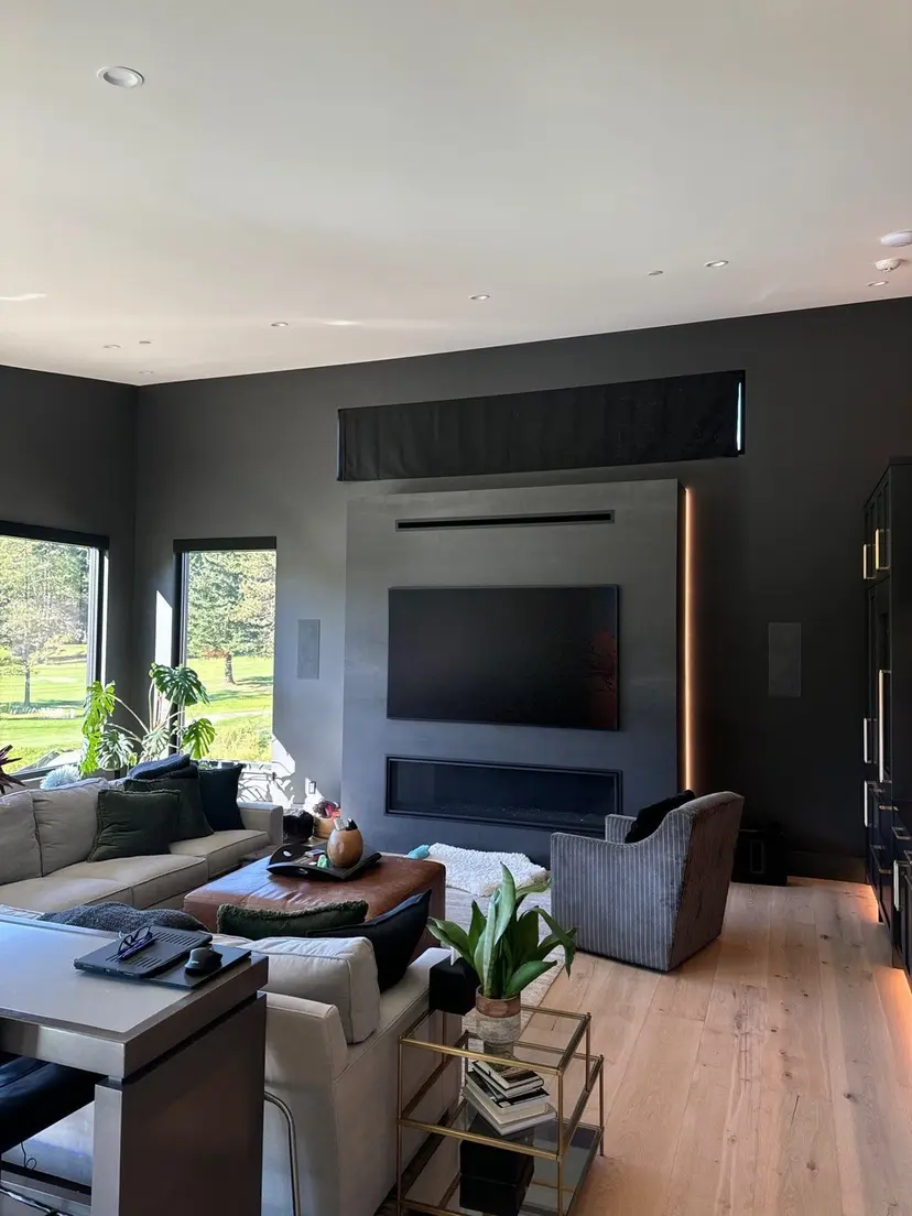 Living room with a linear gas fireplace set into a dark plaster wall and a concealed lighting reveal