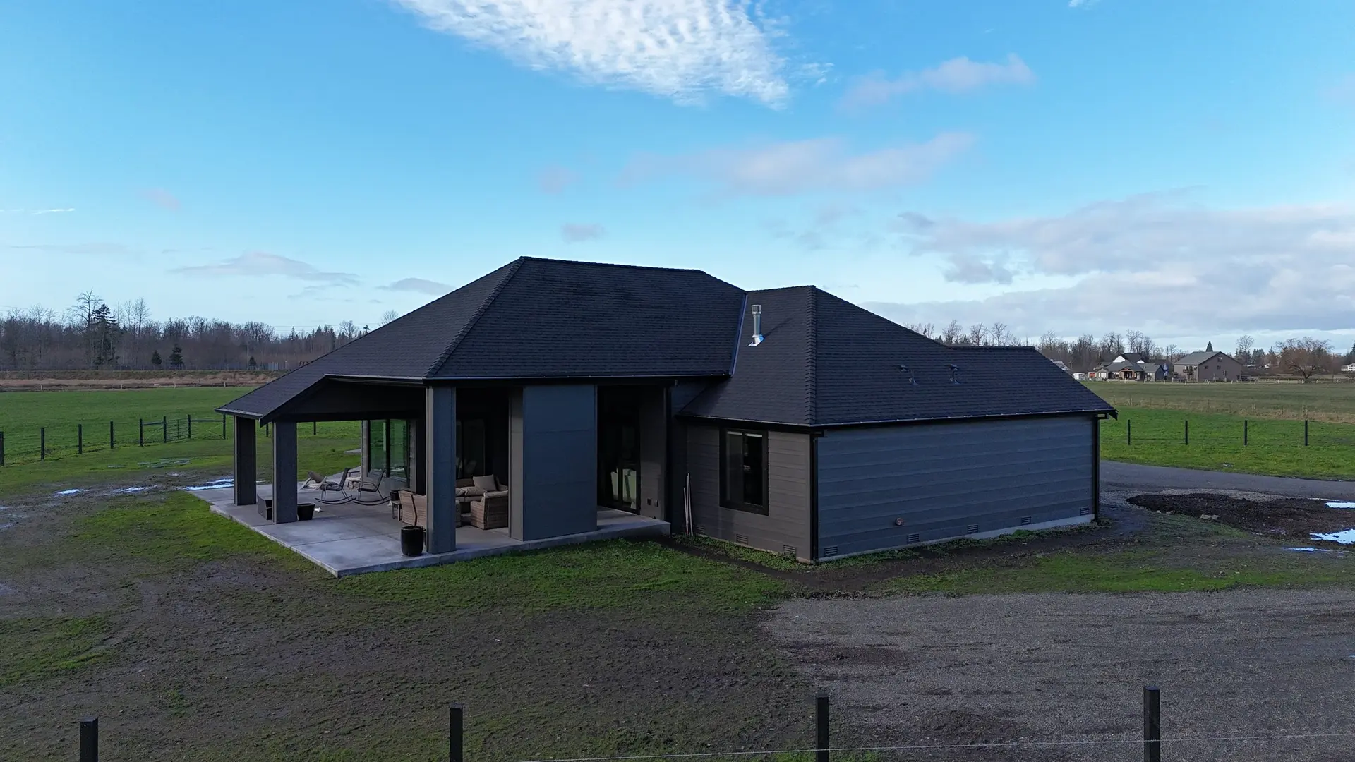 A single-storey home on open acreage with a dark hipped roof and a deep covered patio facing the pasture